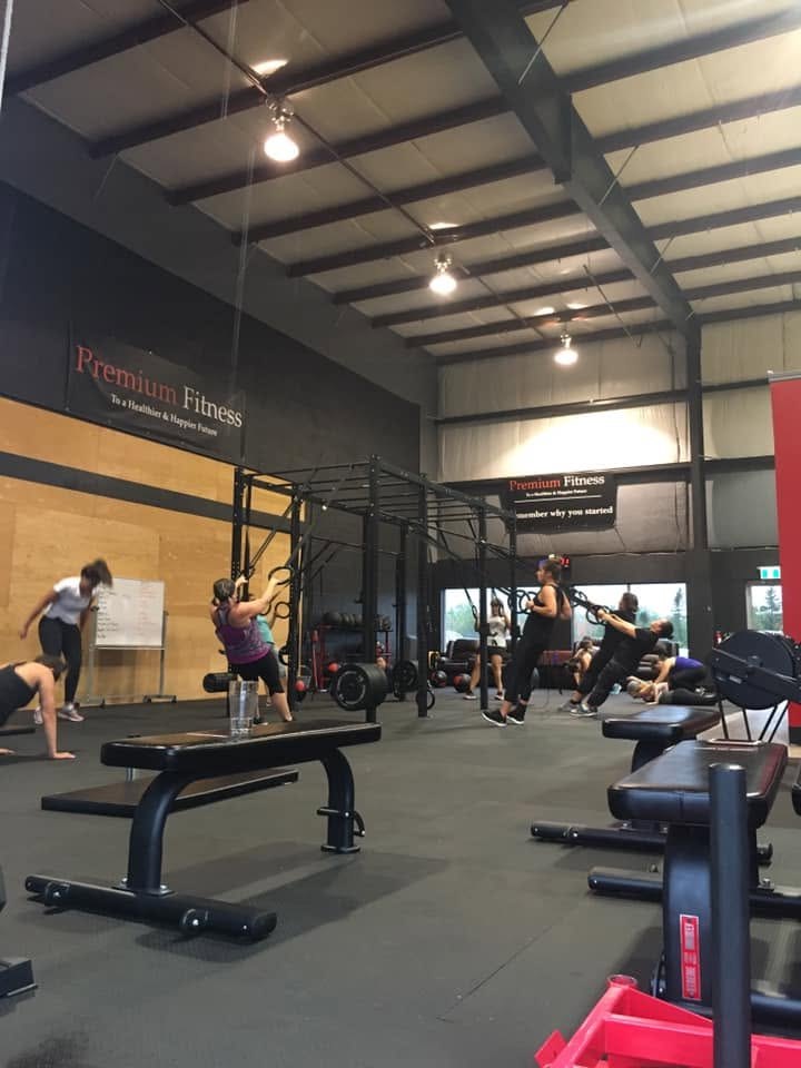 A class training on the Premium Fitness gym floor with rings, rigs and benches